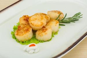 gegrillte Jakobsmuscheln auf dem Teller und Holzhintergrund foto