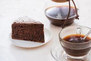 tropfkaffeetropfer und gemahlener kaffee mit glastropfkanne, tasse und schokoladenkuchen