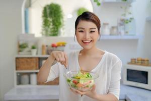 junge asiatische frau, die salatgemüse im diätkonzept isst foto
