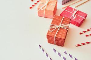 flache Laienkomposition mit hellrosa Geschenkbox, Trinkhalmen, Band und Konfetti. foto