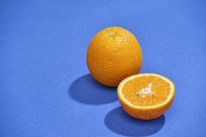 Orange mit der Hälfte der Orange auf dem blauen Hintergrund isoliert foto