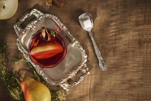 glas apfelweincocktail oder limonade, zimtstangen, anissterne auf hölzernem hintergrund. foto