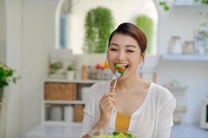 junge asiatische frau, die salatgemüse im diätkonzept isst foto