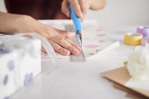 Detail von Frauenhänden, die einige Geschenke mit Geschenkpapier verpacken foto