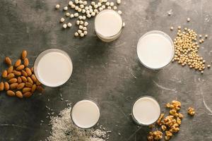 gläser milch mit nüssen macadamia, mandel, soja, reis, lotus. Ansicht von oben. foto