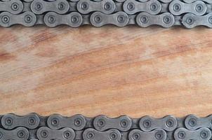 Schmutzige und ölige Kette von einem Mountainbike, das in einem Fahrradgeschäft auf einem Holztisch liegt foto