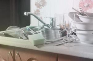 ein riesiger Stapel ungewaschenen Geschirrs in der Küchenspüle und auf der Arbeitsplatte foto