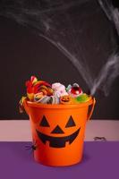 Halloween-Kürbislaterne orange Eimer mit Süßigkeiten foto