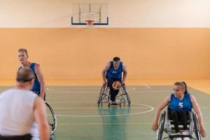 behinderte kriegsveteranen in rollstühlen mit professioneller ausrüstung spielen basketballmatch in der halle.das konzept des sportes mit behinderungen foto