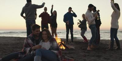 freunde, die sich am herbsttag am strand vergnügen foto