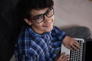 Arabischer Teenager mit Laptop, um zu Hause an Hausaufgaben zu arbeiten foto