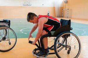 der junge sitzt im rollstuhl und bereitet sich auf den basketballstart des spiels in der großen arena vor foto