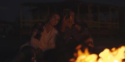 Paar genießt Lagerfeuer mit Freunden am Strand foto