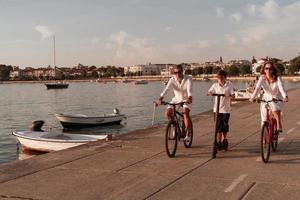 glückliche familie, die zusammen einen schönen morgen am meer genießt, eltern, die fahrrad fahren, und ihr sohn, der einen elektroroller fährt. selektiver Fokus foto