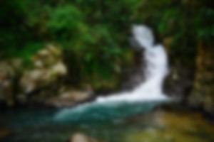 verschwommene Sicht auf den Wasserfall im Bach mit Felsen im Wald foto