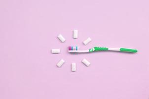 Zahnbürste und Kaugummis liegen auf einem pastellrosa Hintergrund foto