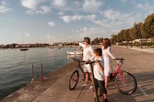 glückliche familie, die zusammen einen schönen morgen am meer genießt, eltern, die fahrrad fahren, und ihr sohn, der einen elektroroller fährt. selektiver Fokus foto