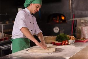 koch bereitet teig für pizza zu foto