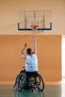 ein kriegsbeschädigter im rollstuhl trainiert mit einem ball in einem basketballverein beim training mit professionellen sportgeräten für behinderte. das Konzept des Sports für Menschen mit Behinderungen foto