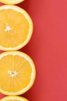 Draufsicht auf mehrere orangefarbene Fruchtscheiben auf hellem Hintergrund in roter Farbe. ein gesättigtes Zitrustexturbild