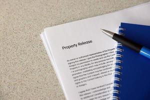 Property-Release-Blankoformular mit blauem Notizblock und blauem Stift liegt auf dem Tisch des Fotografen. Property-Release-Unterzeichnungsfoto foto