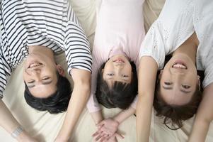 Draufsicht auf asiatische Eltern mit kleinen Töchtern auf dem Bett im Schlafzimmer, glückliches Familienkonzept foto