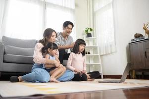 asiatische familie mit kindern, die zu hause einen laptop verwenden foto