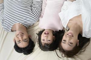 Draufsicht auf asiatische Eltern mit kleinen Töchtern auf dem Bett im Schlafzimmer, glückliches Familienkonzept foto