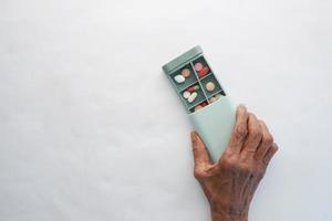 ältere Frauen, die eine medizinische Pillenbox auf weißem Hintergrund halten foto