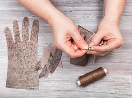 Näherin näht die Echtlederhandschuhe foto