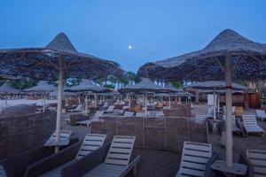 sonnenschirme und sonnenliegen am strand in der nacht mit mond foto