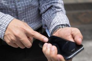 Nahaufnahme einer Hand eines Mannes, die mit einem Mobiltelefon im Freien einen Sitzstuhl im öffentlichen Park verwendet. mit Filtertönen Vintage-Effekt, warme Töne. foto