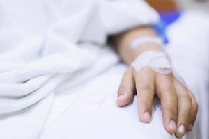 Nahaufnahme Menschen konzentrieren sich auf die Hand eines kranken Patienten auf dem Bett in der Krankenstation. Gesundheitswesen und Medizin. Linie Kochsalzlösung und Pulsdetektor Blutsauerstoffmessgerät am Finger der Menschen. foto