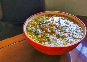 Instant-Nudelsuppe in rosa Schüssel auf braunem Holztisch. foto