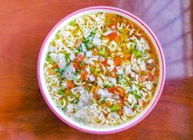 Instant-Nudelsuppe in rosa Schüssel auf braunem Holztisch. foto