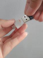 eine hand versucht, eine kleine kolbenscheibe in einen adapter usb typ c auf usb 3.0 typ-c adapter otg einzulegen foto