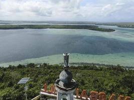 luftaufnahme der jesusstatue mit wunderschönem strandblick auf einer kleinen insel. maluku, indonesien - juli 2022 foto