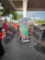 Defokussierte abstrakte Unschärfe von Menschen, die Motorräder an Tankstellen betanken foto