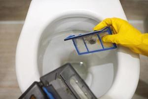 Hände in Gummihandschuhen werfen Müll in Toilette, Nahaufnahme. foto