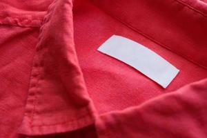 weißes leeres Kleidungsetikett auf rotem Leinenstoff-Texturhintergrund foto