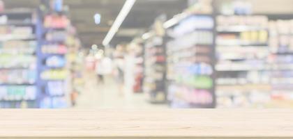 leere hölzerne tischplatte mit supermarktgang mit produktregalen innen defokussierter unschärfehintergrund foto