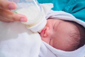 mutter, die neugeborenes baby aus der flasche füttert foto