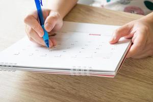 Frauenhand mit Stift schreiben auf Kalenderdatum Geschäftsplanungstermin Besprechungskonzept foto