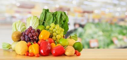 frisches obst und gemüse auf holztisch mit supermarkt-lebensmittelgeschäft unscharfer defokussierter hintergrund foto