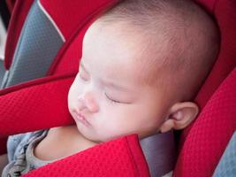 Asiatisches Babymädchen schläft im Autositz mit Sicherheitsgurt für Sicherheitsreisen foto