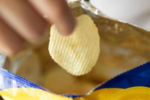 hand halten kartoffelchips mit snackbeutel foto