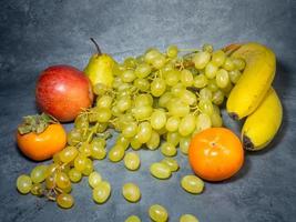 Stillleben mit Früchten. Apfel, Kaki, Birne und Trauben auf schwarzem Hintergrund. Persimone Kamille. Apfel Gala. Birne Lucas. gesundes Essen. foto