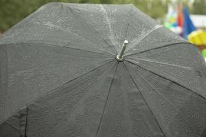 schwarzer Regenschirm in Regentropfen. großer Regenschirm. nasses Wetter. foto