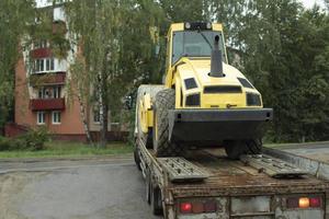 Transport von schweren Maschinen. Traktor auf Plattform. Baumaschinen auf LKW-Anhänger. foto