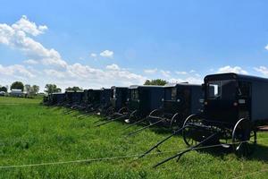 Amische Farm mit ein paar Buggys, die auf einem Feld geparkt sind foto